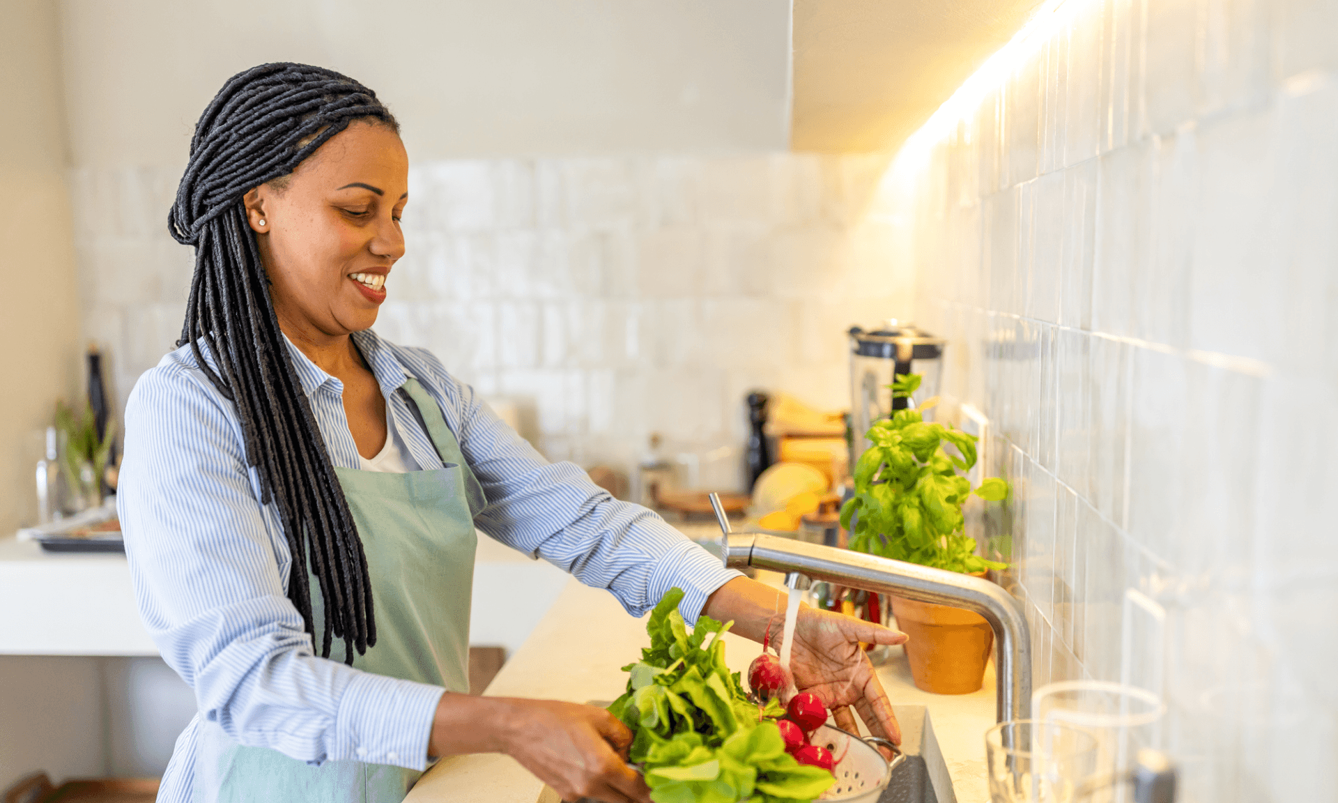 A woman rinsing greens in her kitchen sink