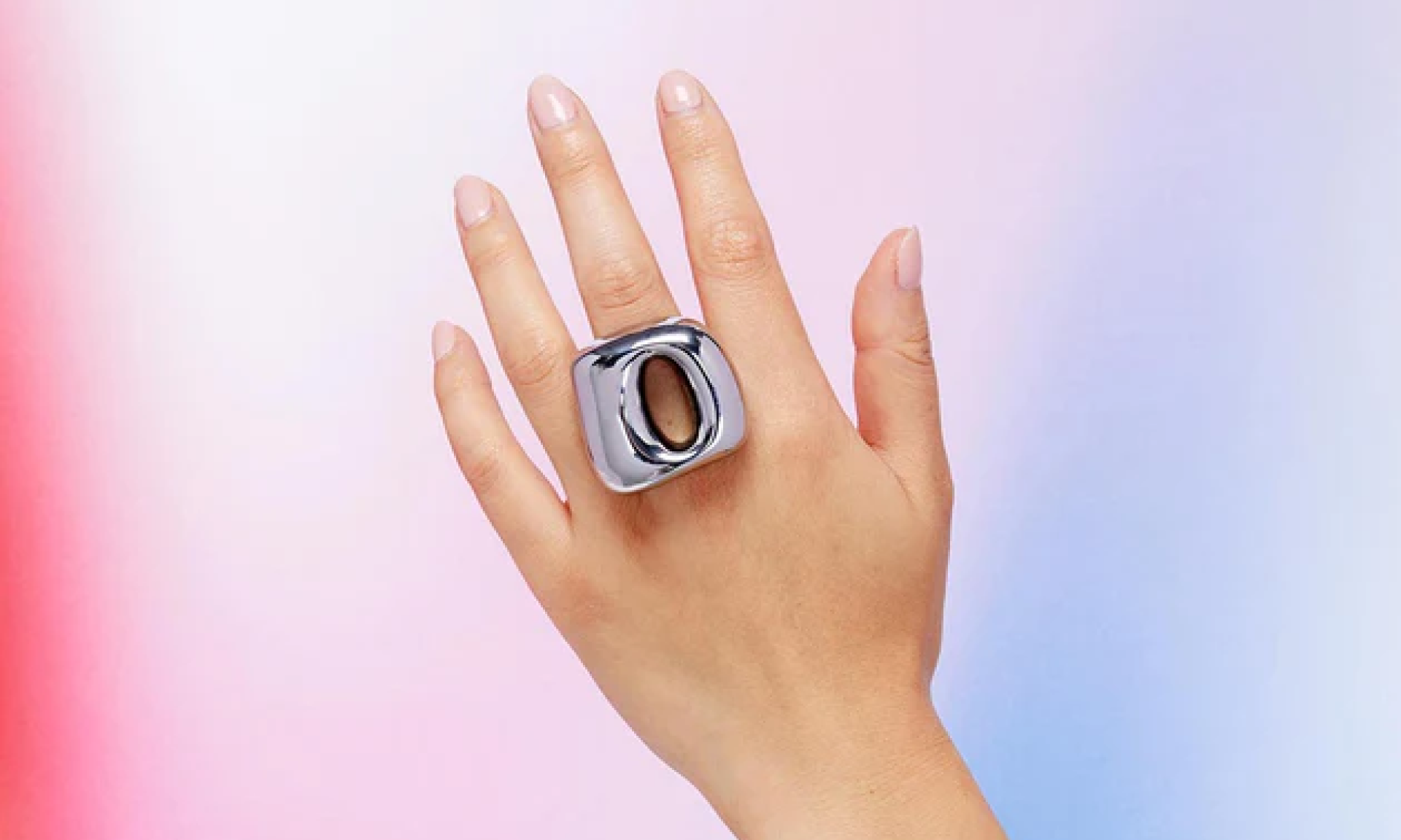 Hand wearing Unbound Flick in silver on pink and blue gradient background